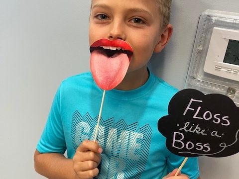 A young dental patient promotes dental hygiene with a sign 